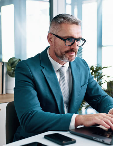 Man in a teal blazer working on a laptop